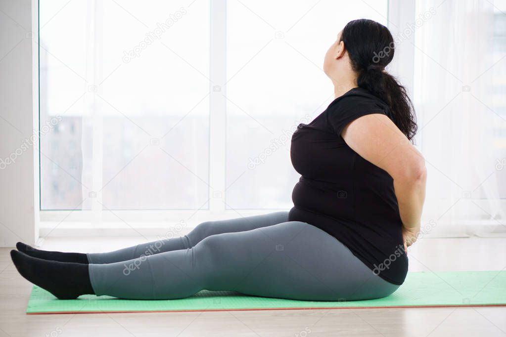 overweight woman practicing yoga in studio