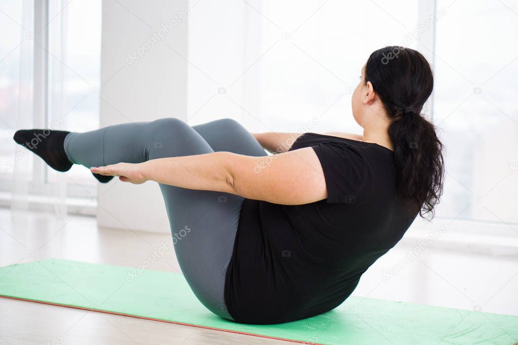 overweight woman do static exercise in yoga studio