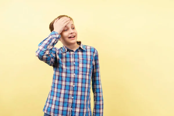 Tafatt generad pojke täcker pannan med handen — Stockfoto
