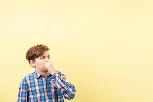 Garçon avec expression dégoûtée du visage couvrant le nez — Photo