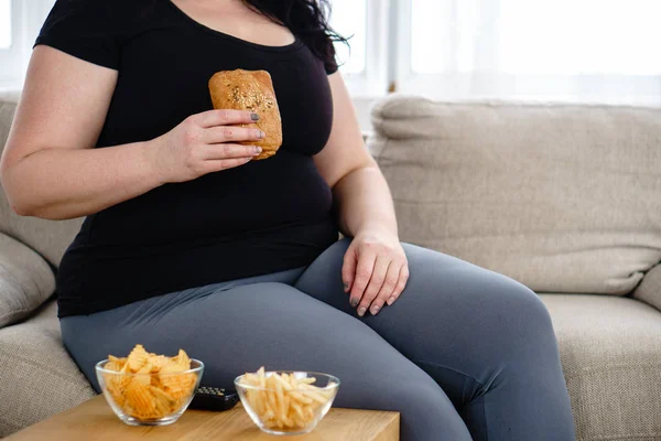 Mujer gorda viendo series en la televisión comiendo comida chatarra — Foto de Stock