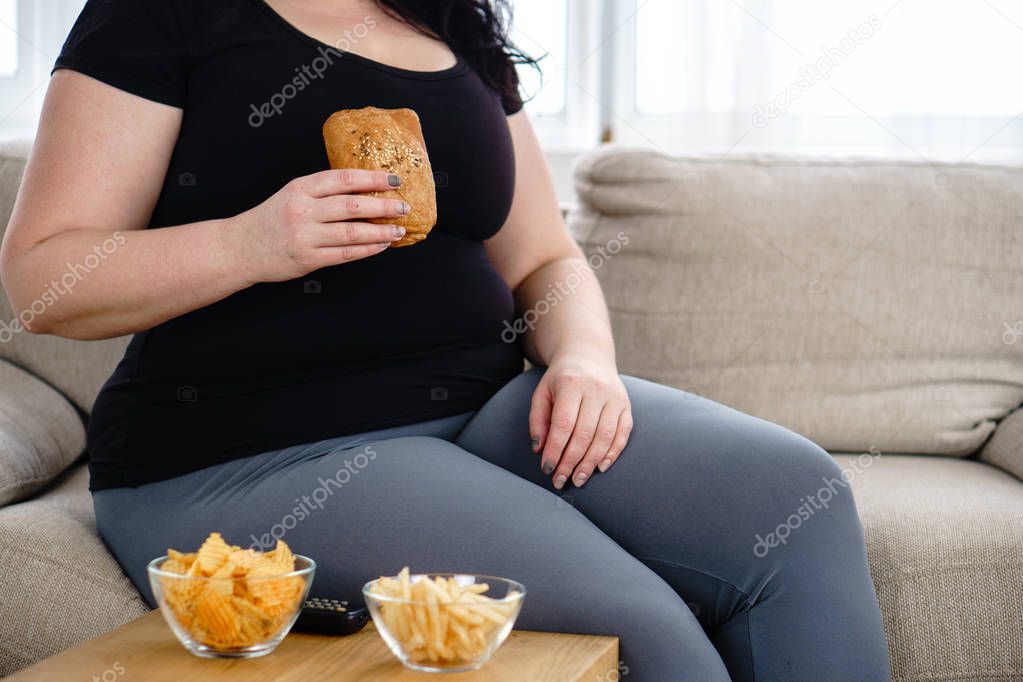 fat woman watching series at tv eating junk food
