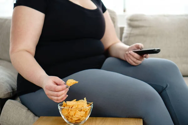 Mujer con sobrepeso con televisión remota y comida chatarra — Foto de Stock