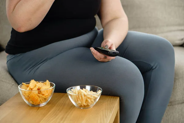 Товста жінка дивиться серіал на телебаченні їсть нездорову їжу — стокове фото