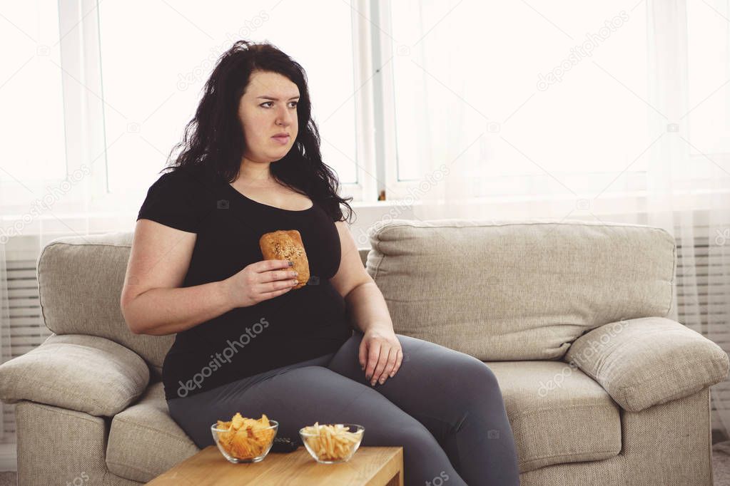 fat woman watching series at tv eating junk food