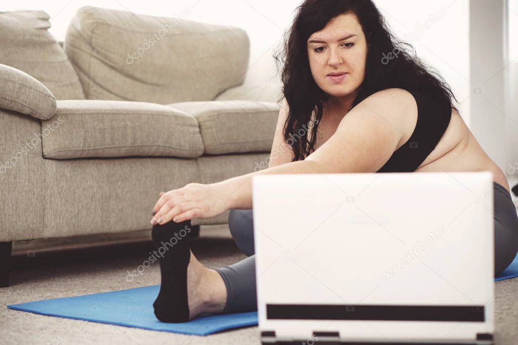 overweight woman practicing yoga. home training