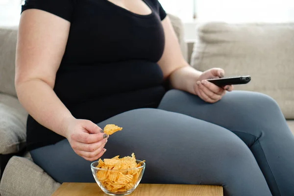 Mulher com sobrepeso com tv remoto e junk food — Fotografia de Stock