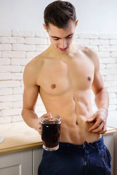 Fitter Mann mit muskulösem Körper, der einen Becher dunkles Bier in der Hand hält — Stockfoto