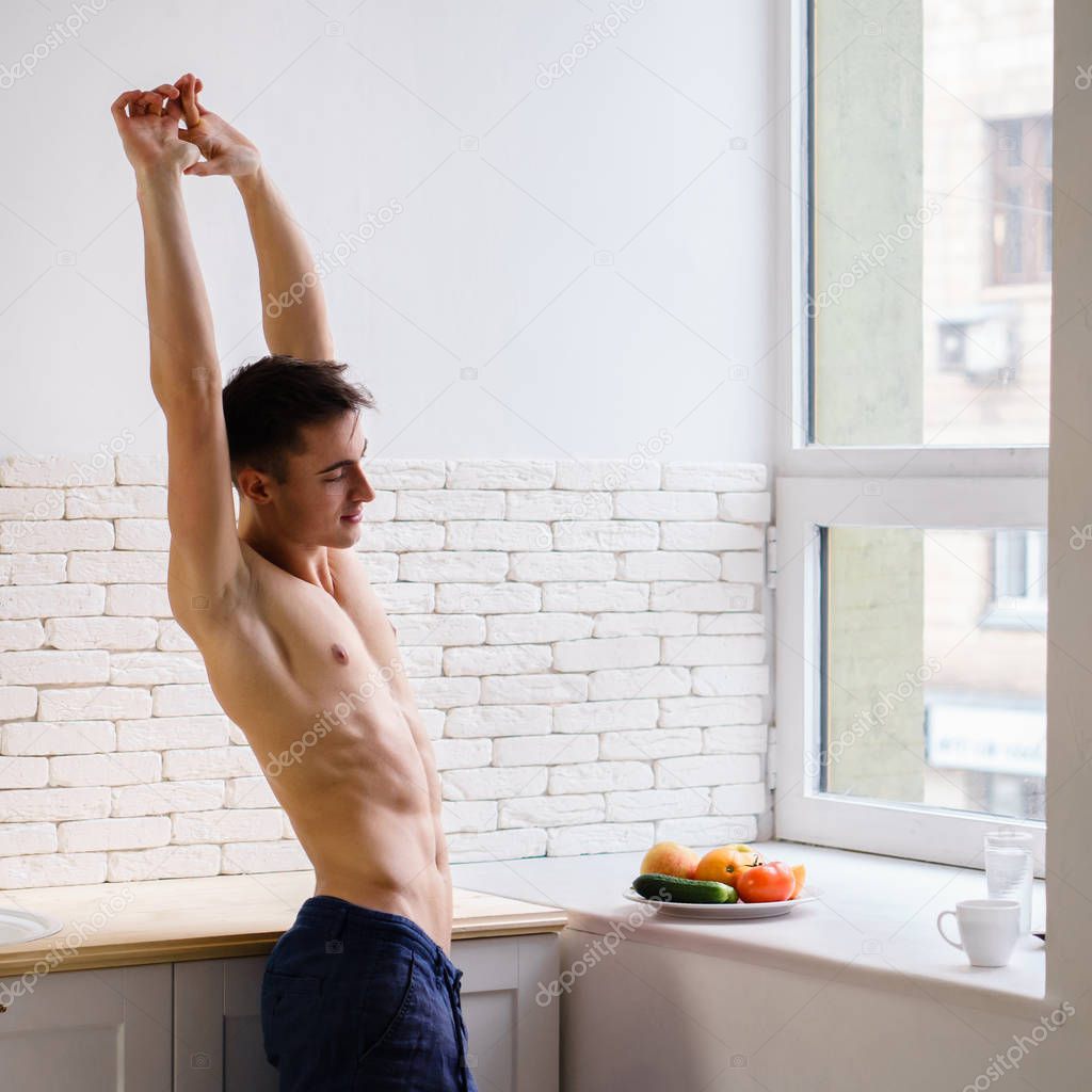 young fit smiling man stretching at home kitchen
