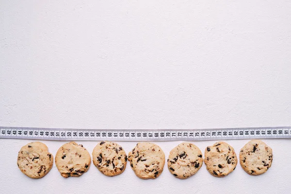 diet. chocolate cookie background and measure tape