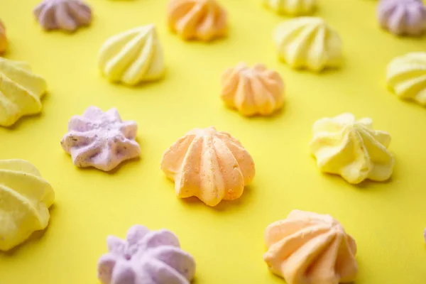 Biscoitos merengue coloridos no fundo amarelo — Fotografia de Stock