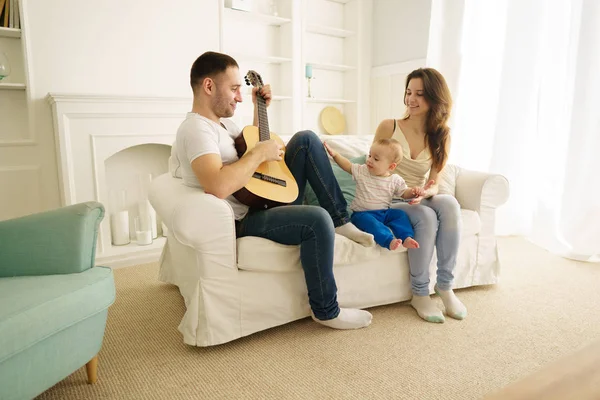 father playing guitar for mother and son. leisure