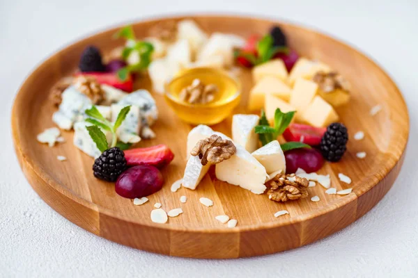 Асортимент різних сирів на дерев'яній тарілці — стокове фото