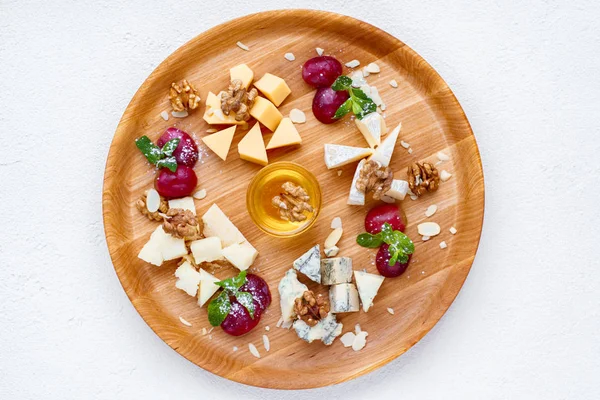 Сирна тарілка подається з виноградом, медом та горіхами — стокове фото