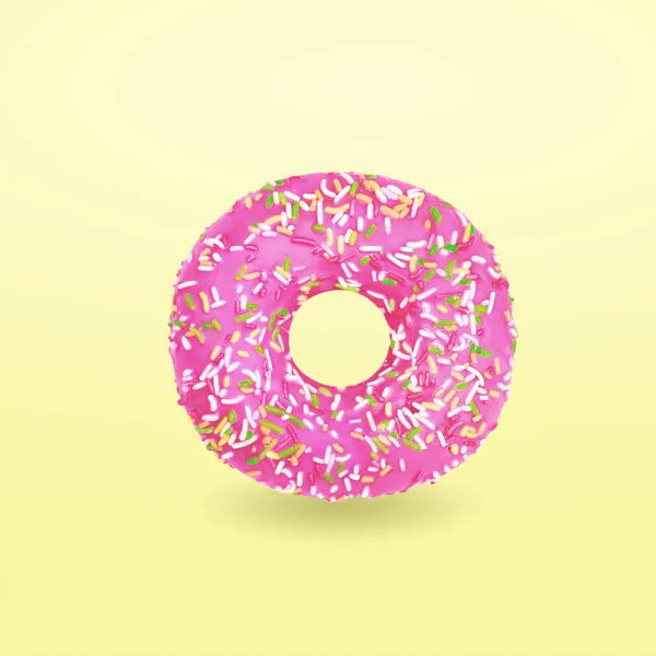 Pink donut with icing on yellow background