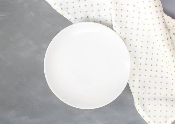 Empty white circle plate on wooden table with linen napkin. Overhead view.