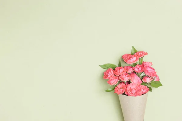 Bouquet of small red roses in vintage paper on the table.