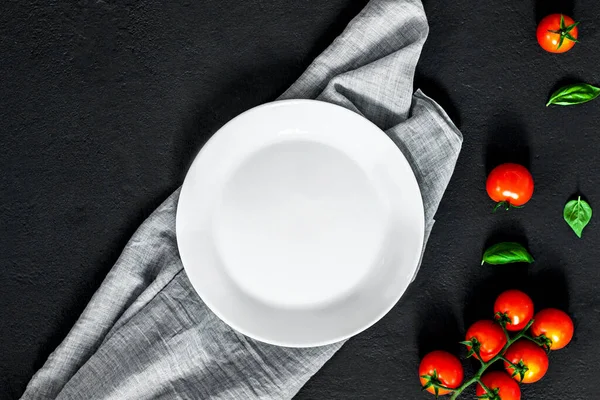 Empty plate. ?lassic italian food background tomato, basil on dark table. Top view.