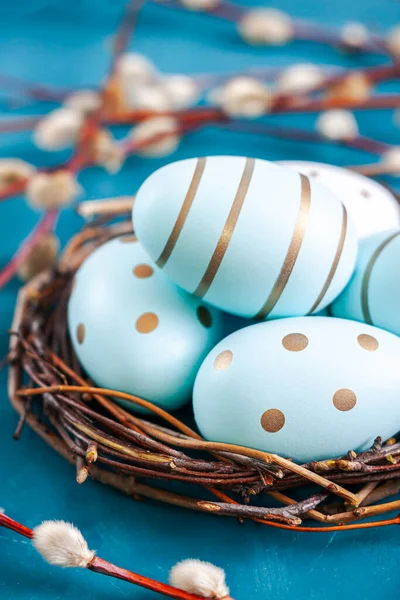 Easter background with Easter eggs in bird nest on blue background. Spring holiday.