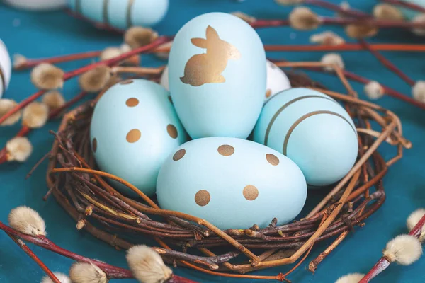 Easter background with Easter eggs in bird nest on blue background. Spring holiday.