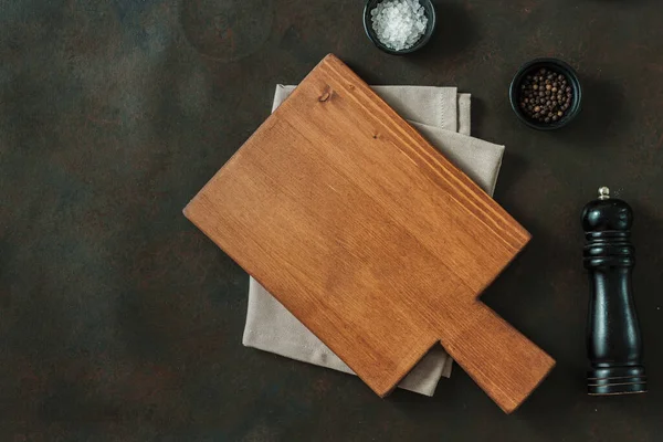 Wood cutting board over towel on stone kitchen table. Top view. Food background Cutting board wood table