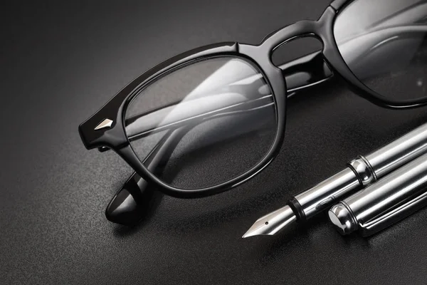 Gafas de plástico negro y pluma estilográfica — Foto de Stock