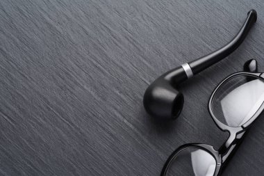 Koyu kayrak backgr üzerinde sigara boru ile siyah plastik gözlük