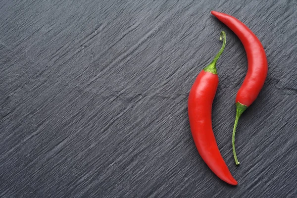 Poivrons rouges sur fond d'ardoise noire foncée avec espace de copie — Photo