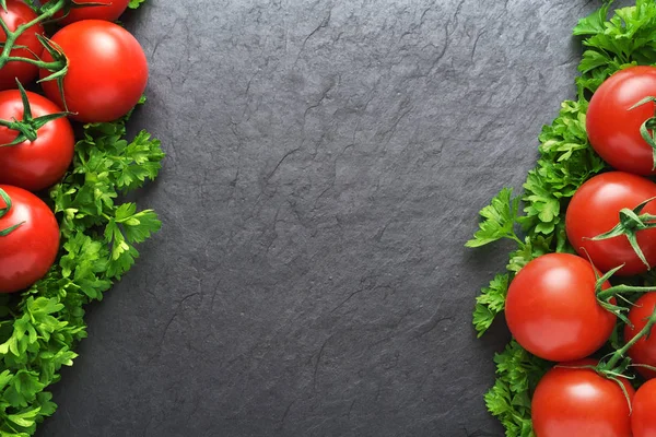 Czerwone pomidory i pietruszka na czarnym łupku z kopią przestrzeni — Zdjęcie stockowe