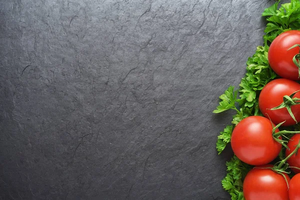 Rode tomaten en peterselie op zwarte leisteen met Kopieer ruimte — Stockfoto