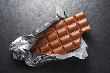 Siyah kayrak arka plan üzerinde tam sütlü çikolata bar