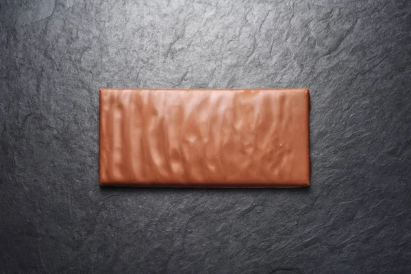 Empty milk chocolate bar on black slate background — ストック写真