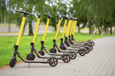 Arka arkaya dizilmiş sarı motorlu scooterlar. Scooter paylaşım sistemi.