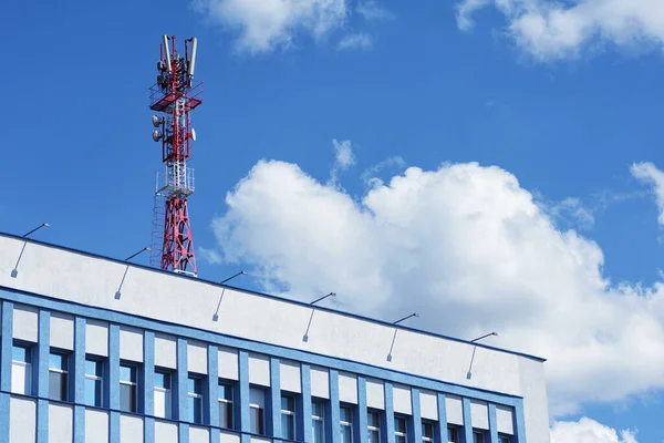青い空と雲の建物の上のテレコムセルラー基地局タワー — ストック写真