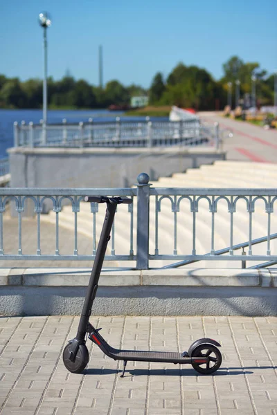 Çitin yakınındaki baraj kaldırımında gri elektrikli scooter.