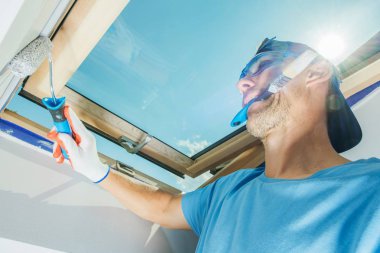 Oda ressam çoklu görev. Beyaz inşaat işçisi boya fırça rulo kullanarak onun ağız boyama Duvar ile.