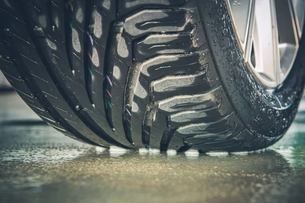 全新汽车轮胎胎面特写照片 汽车车轮在潮湿的路面上 — 图库照片