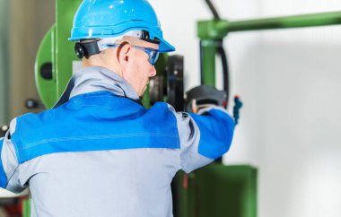 Profesyonel ağır iş makineleri operatör. Makine konsol önünde mavi baret beyaz metal işleme sanayi işçisi. Endüstriyel Tema.