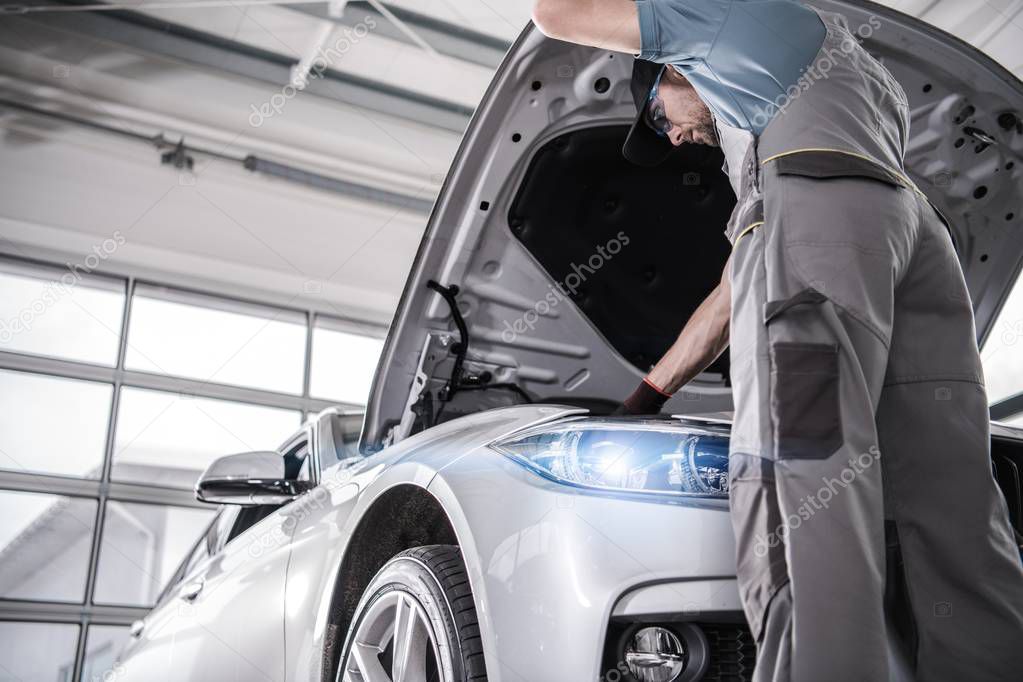 Modern Certified Car Service. Caucasian Mechanic in His 30s Checking Crucial Elements of the Engine During Scheduled Warranty Maintenance.
