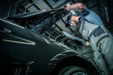 Servicing Modern Car. Pre Owned Vehicle Inside Auto Service. Caucasian Car Mechanic in His 30s Taking Look Under the Hood. Automotive Theme. clipart