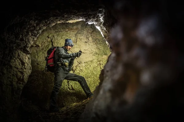 Deep Cave Exploration by Men with Flashlights and Backpack. Caucasian Caver in the Grotto.