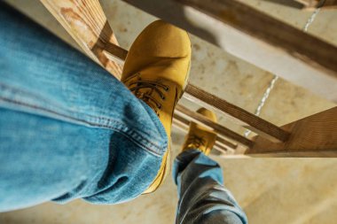 Construction Worker on Wooden Ladder. Shoes Closeup Photo.  clipart