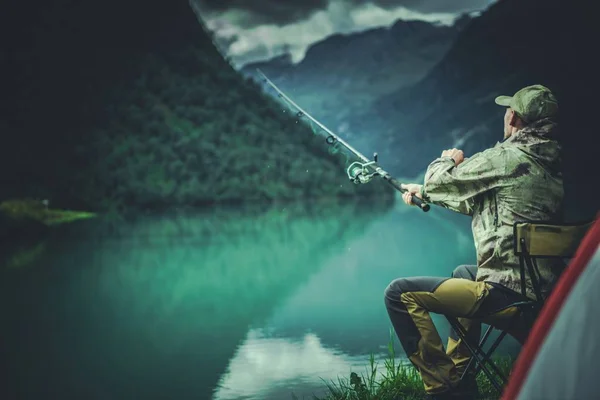 Glacial Lake Fly Fishing. Caucasian Fisherman on a Lake Shore.
