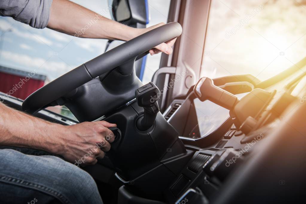 Euro Truck Driving. Modern Semi Truck Cabin Interior. Caucasian Trucker Placing Hand on a Steering Wheel. 