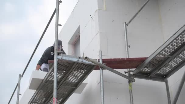 Arbeiter Bewegt Isolierblöcke Auf Einem Gerüst — Stockvideo