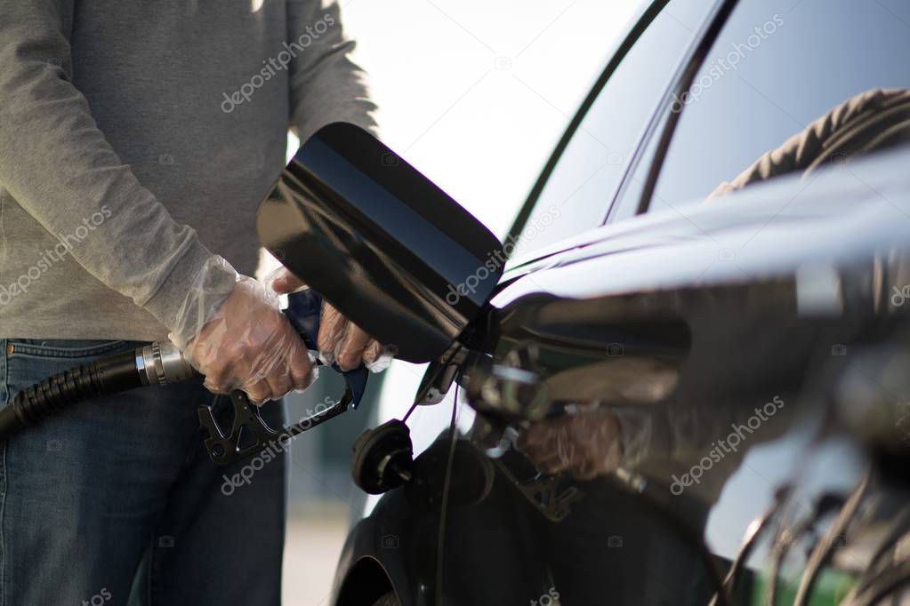 Caucasian Driver Refueling His Modern Car Using Plastic Gloves. Gas Station Concept.