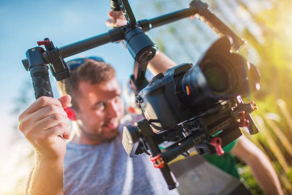 DSLR Digital Video Camera on a Gimbal. Caucasian Cameraman with Motion Picture Camera Installed on Professional Stabilizator.