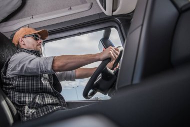 Beyaz sürücü Modern yarı kamyon kabin içinde güneş gözlüğü takıyor. Ulaşım ve Otomotiv Sanayi. Ticari sürüş.