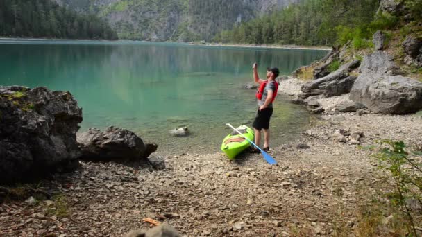 Kayaker шукає стільникового сигналу в його смартфон на краю мальовничі озера — стокове відео