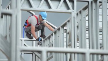 Beyaz Müteahhit 30'lu yaşlarında Matkap Sürücüsü Elektrikli Aletile Yükseklikte Çalışıyor. İskelet Çelik İnşaat İşi.